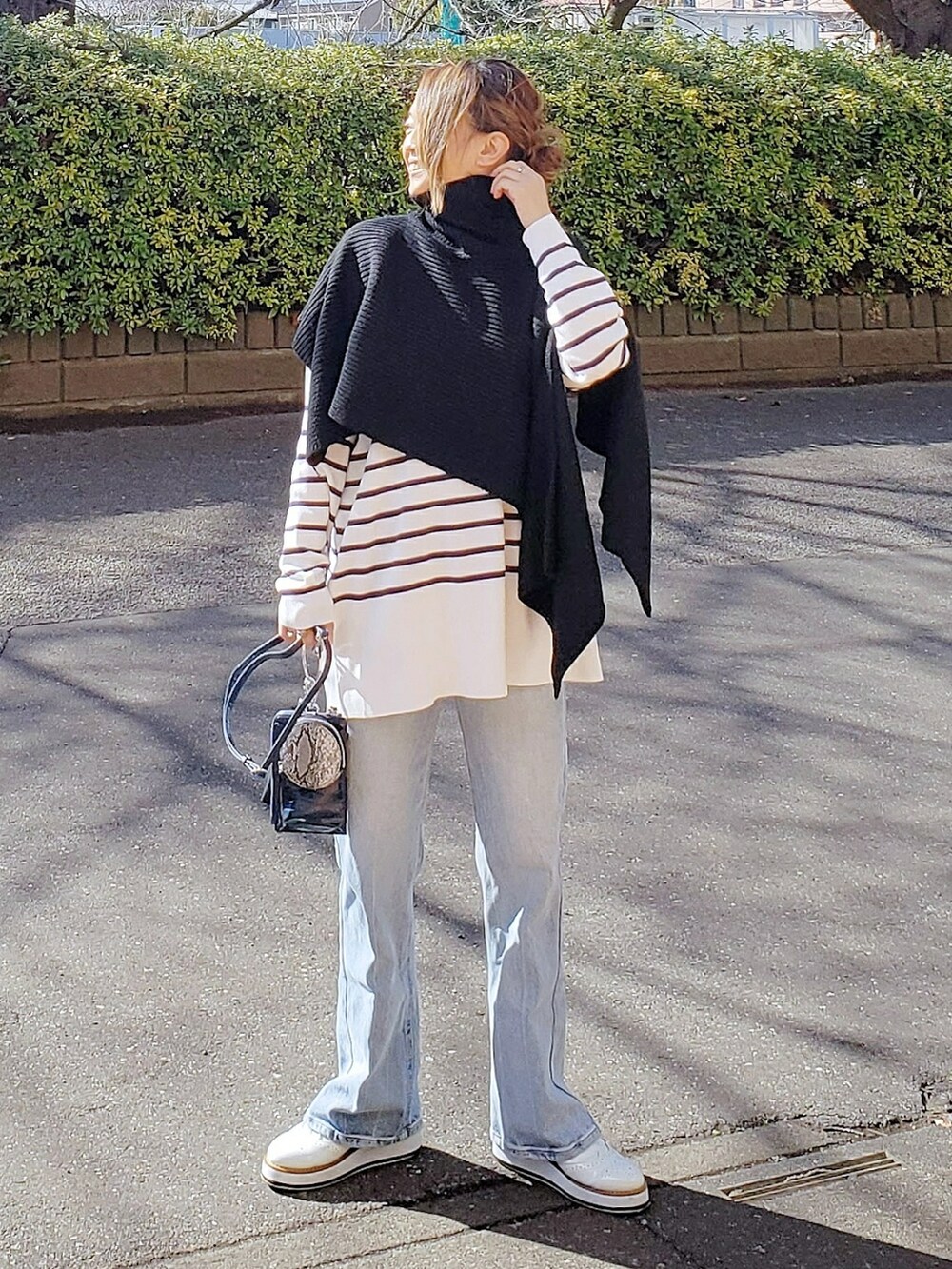 ブラック系のベスト、ホワイト系のニット/セーター、ブルー系のデニムパンツを着用したレディースの冬コーディネートの2枚目の写真