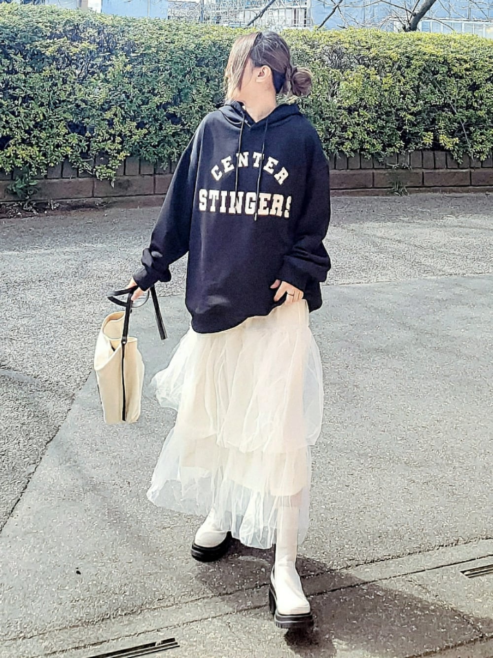ブラック系のパーカー、ホワイト系のスカート、ホワイト系のブーツを着用したレディースの春コーディネートの3枚目の写真