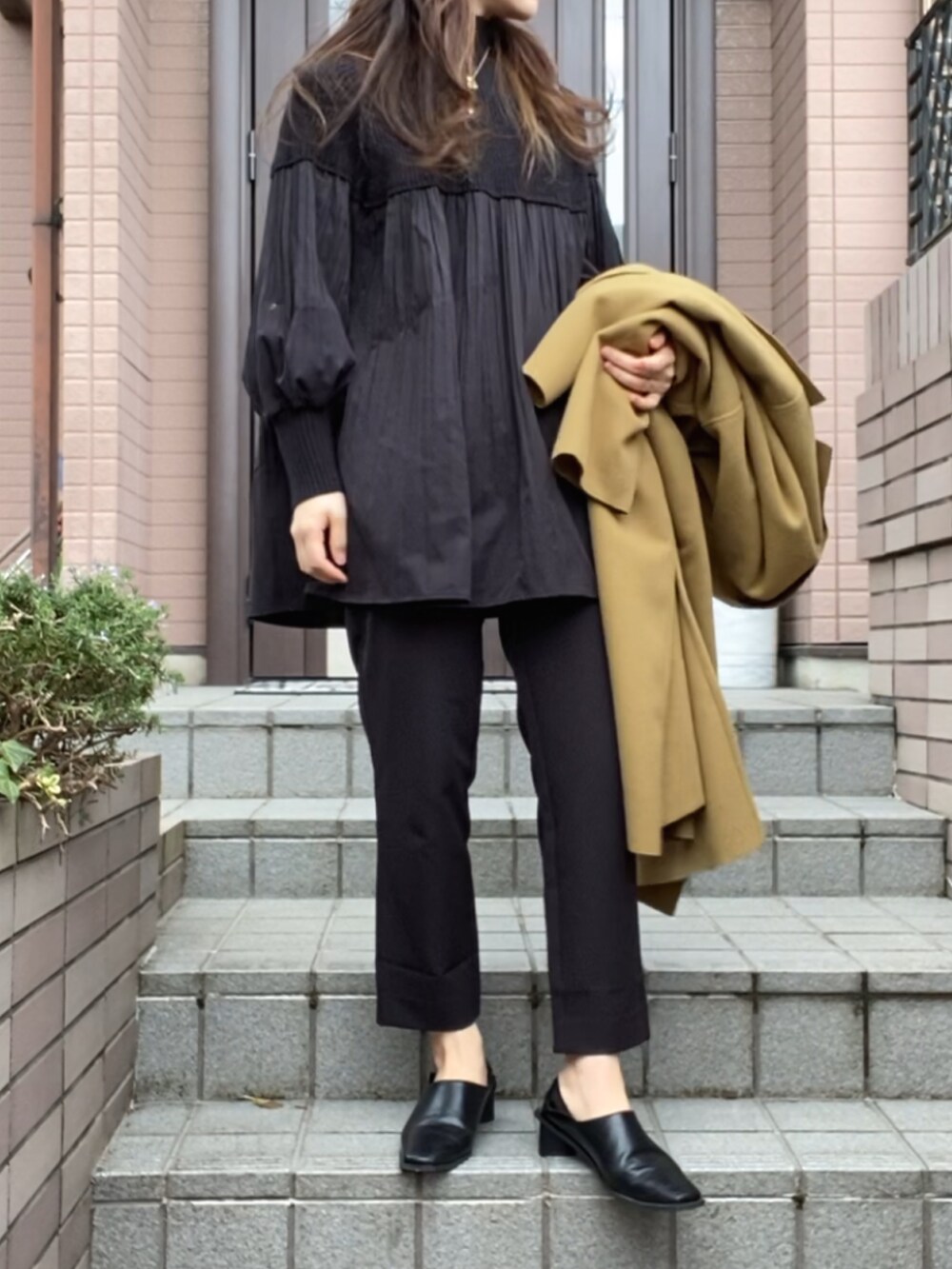 ブラック系のニット/セーター、ホワイト系のショルダーバッグ、ブラック系のパンツを着用したレディースの冬コーディネートの2枚目の写真