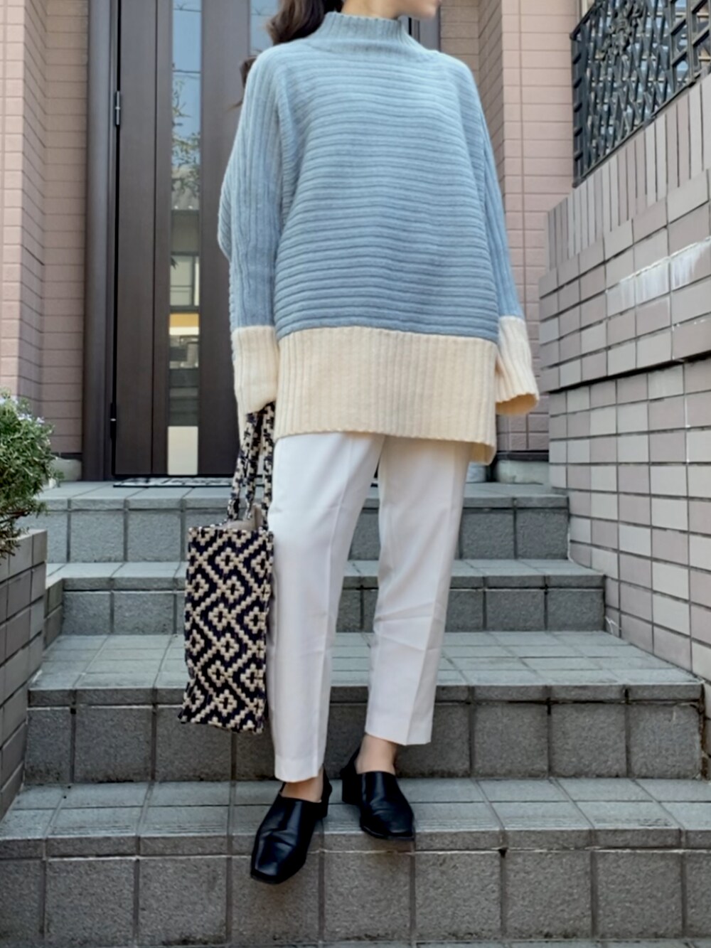 ブルー系のニット/セーター、ブルー系のバッグ、ホワイト系のスラックスを着用したレディースの冬コーディネートの2枚目の写真