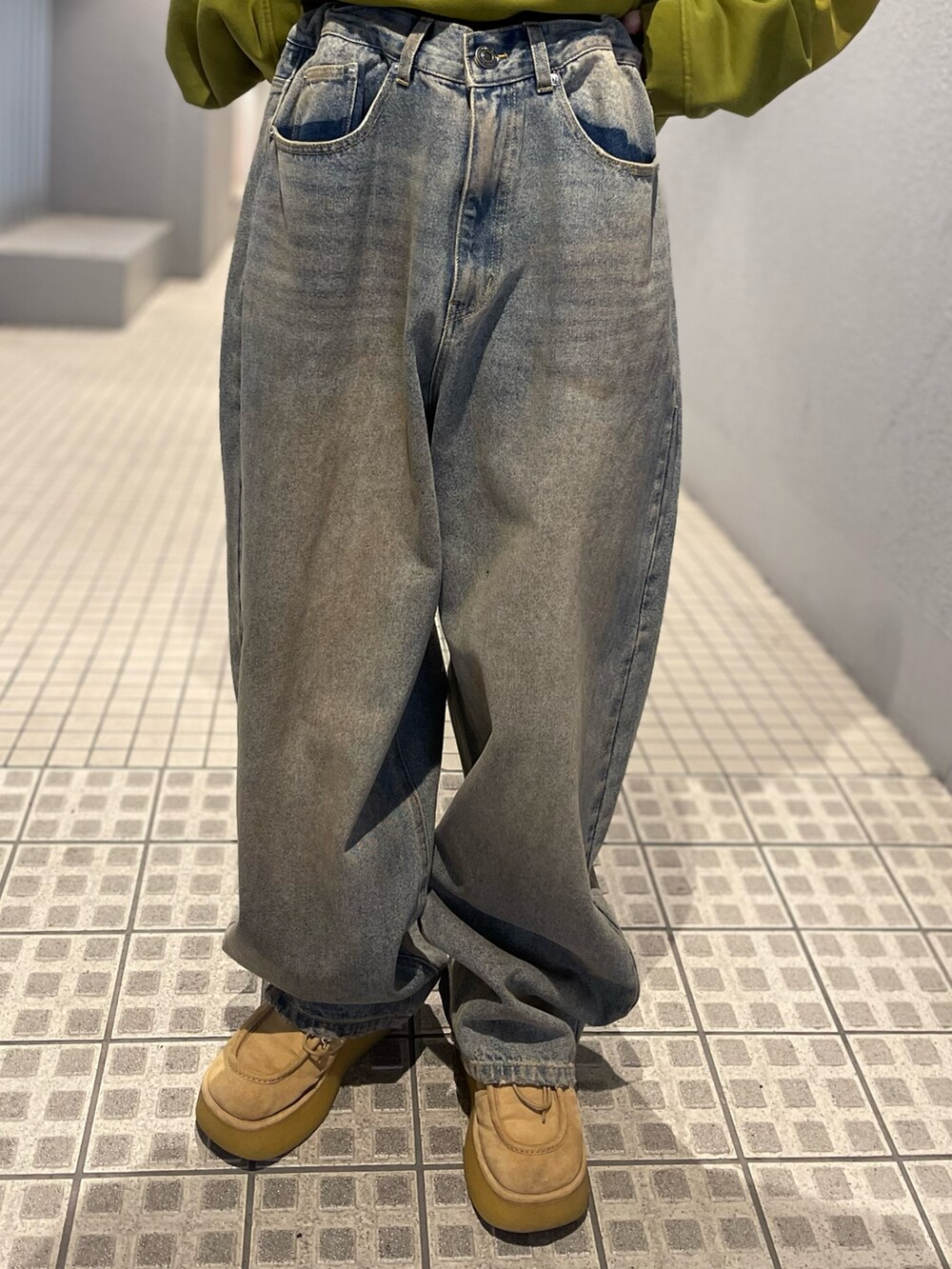 イエロー系のパーカー、その他のデニムパンツ、グリーン系のサングラスを着用したレディースの冬コーディネートの3枚目の写真
