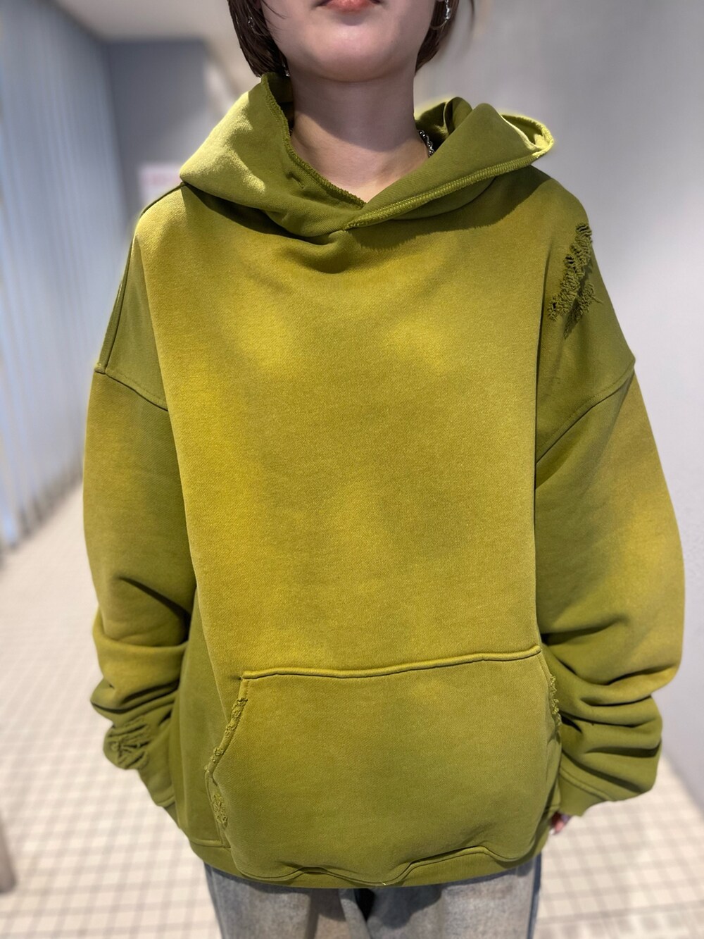 イエロー系のパーカー、その他のデニムパンツ、グリーン系のサングラスを着用したレディースの冬コーディネートの2枚目の写真