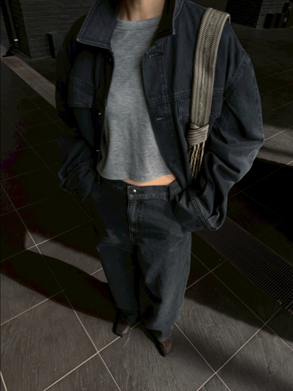 ブラック系のデニムジャケット、ブラック系のデニムパンツ、ブラック系のサンダルを着用したレディースの春コーディネートの2枚目の写真