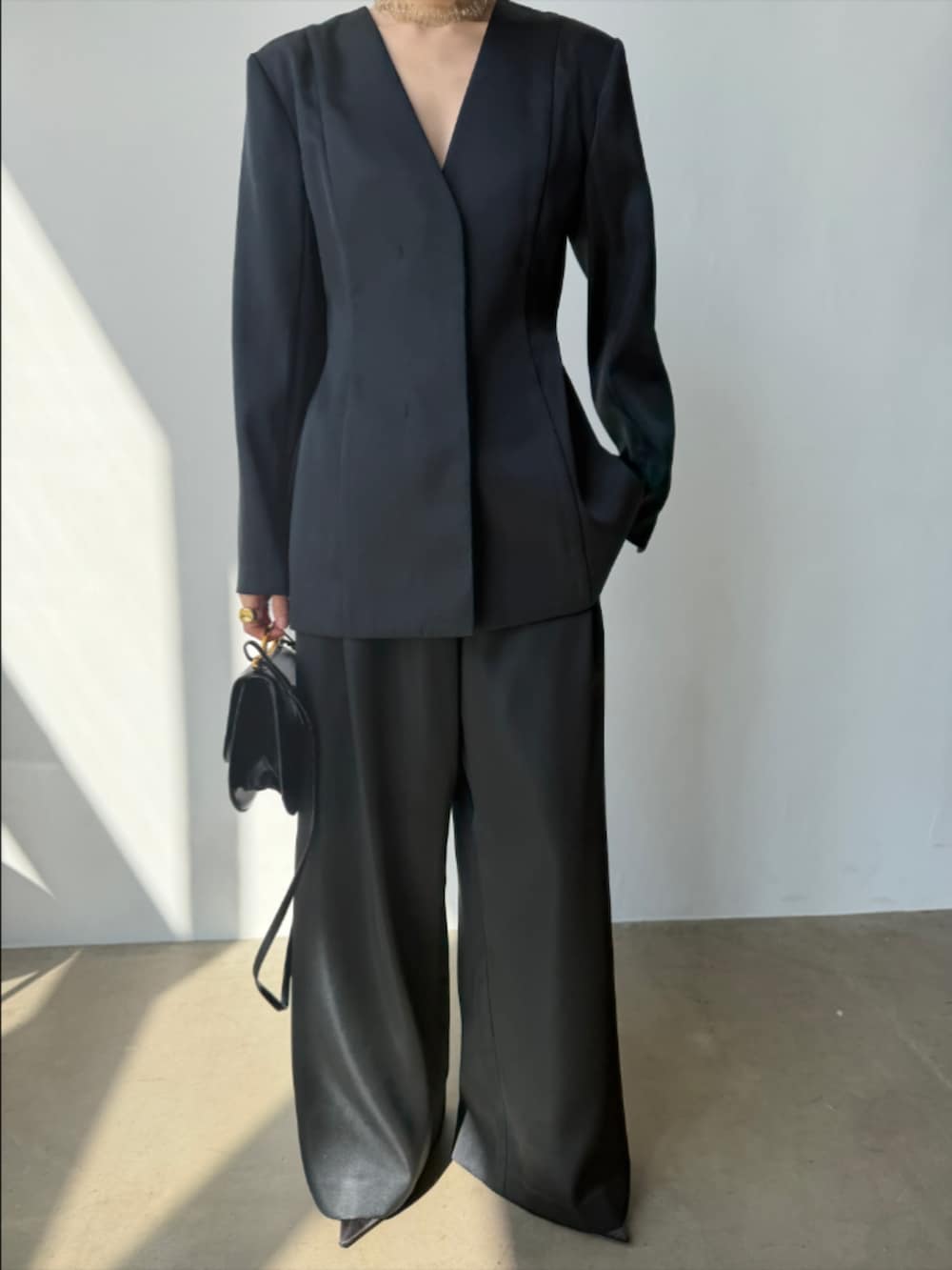 ブラック系のスラックス、ブラック系のパンプス、ブラック系のテーラードジャケットを着用したレディースの春コーディネートの3枚目の写真