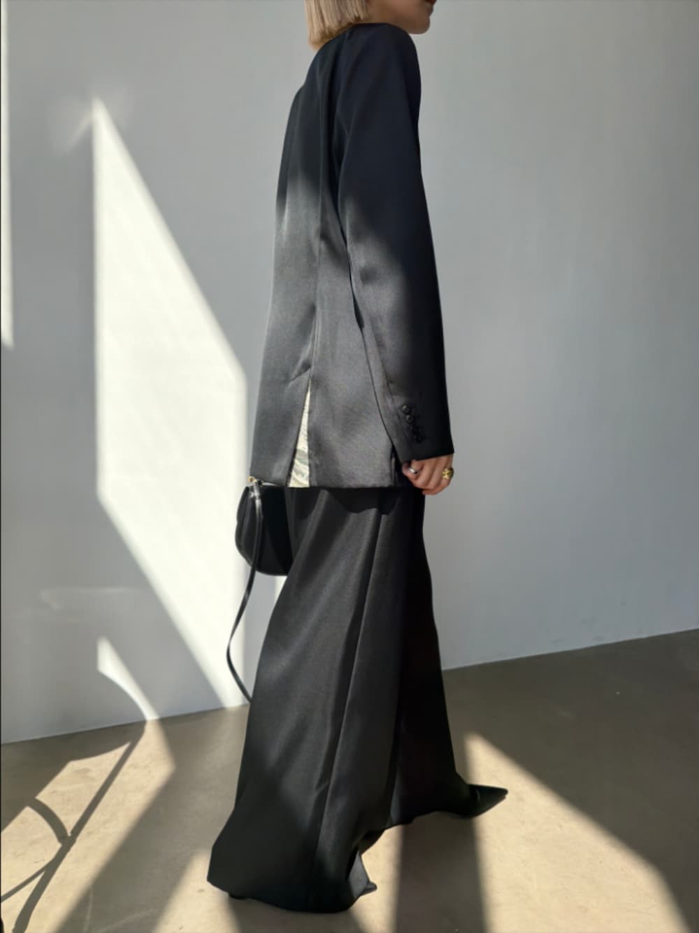 ブラック系のスラックス、ブラック系のパンプス、ブラック系のテーラードジャケットを着用したレディースの春コーディネートの2枚目の写真