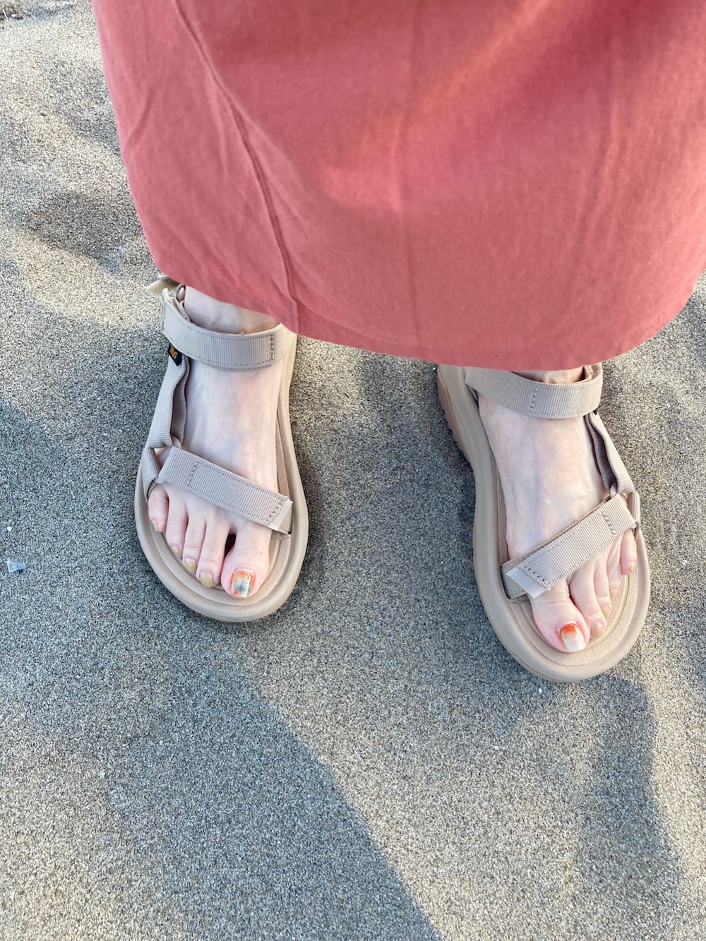 オレンジ系のワンピース、ベージュ系のサンダル、ホワイト系のトートバッグを着用したレディースの夏コーディネートの5枚目の写真