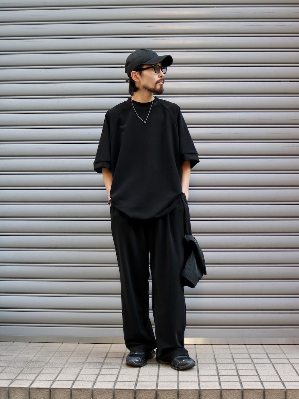 ブラック系のTシャツ/カットソー、ブラック系のトートバッグ、ブラック系のスラックスを着用したメンズの夏コーディネートの2枚目の写真