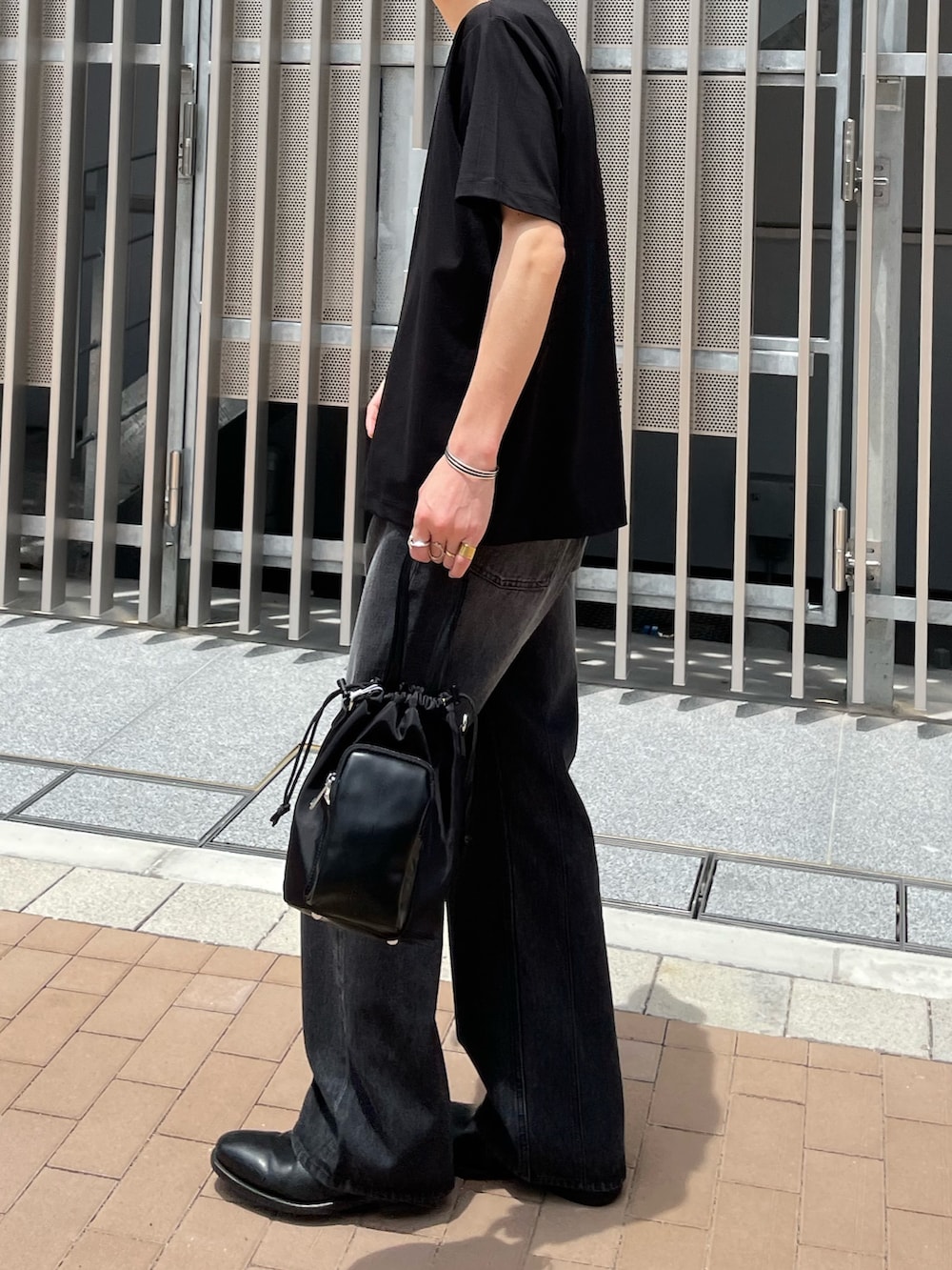 ブラック系のTシャツ/カットソー、ブラック系のデニムパンツ、ブラック系のショルダーバッグを着用したメンズの夏コーディネートの2枚目の写真
