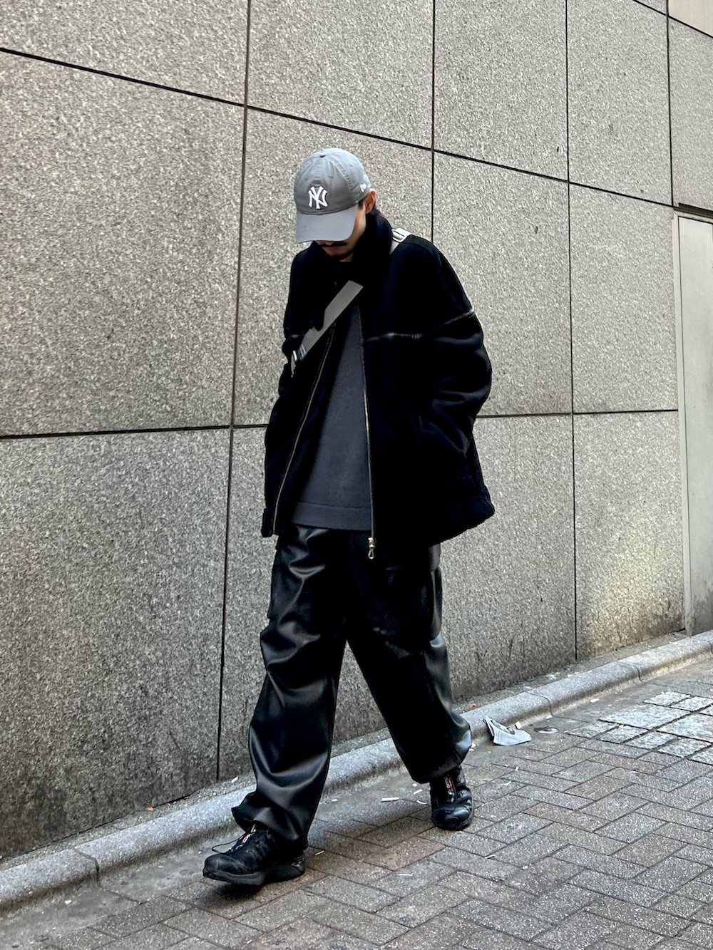 グレー系のニット/セーター、ブラック系のジャケット/アウター、グレー系のショルダーバッグを着用したメンズの冬コーディネートの2枚目の写真