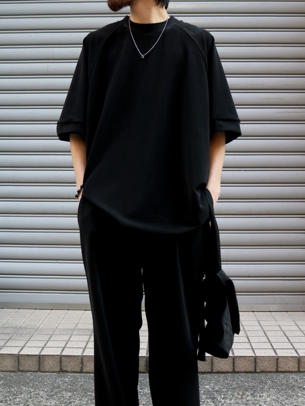 ブラック系のTシャツ/カットソー、ブラック系のトートバッグ、ブラック系のスラックスを着用したメンズの夏コーディネートの4枚目の写真