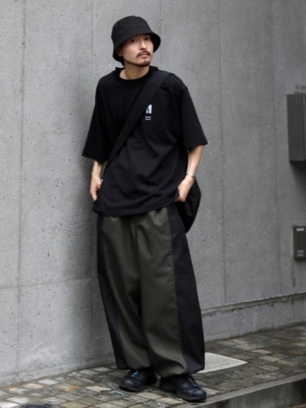 ブラック系のTシャツ/カットソー、ブラック系のスニーカー、グリーン系のカーゴパンツを着用したメンズの夏コーディネートの2枚目の写真