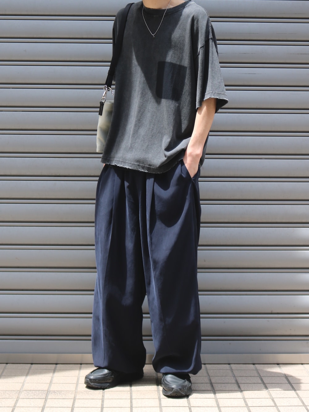 ブルー系のその他パンツ、ブラック系のTシャツ/カットソー、ホワイト系のショルダーバッグを着用したメンズの夏コーディネートの2枚目の写真