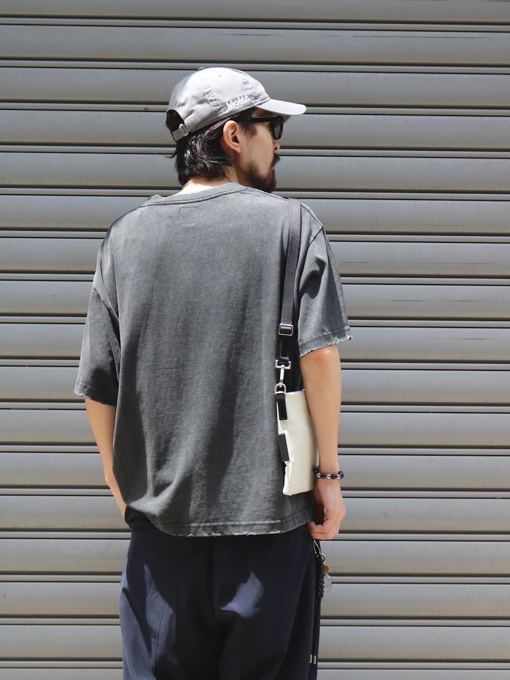 ブルー系のその他パンツ、ブラック系のTシャツ/カットソー、ホワイト系のショルダーバッグを着用したメンズの夏コーディネートの4枚目の写真