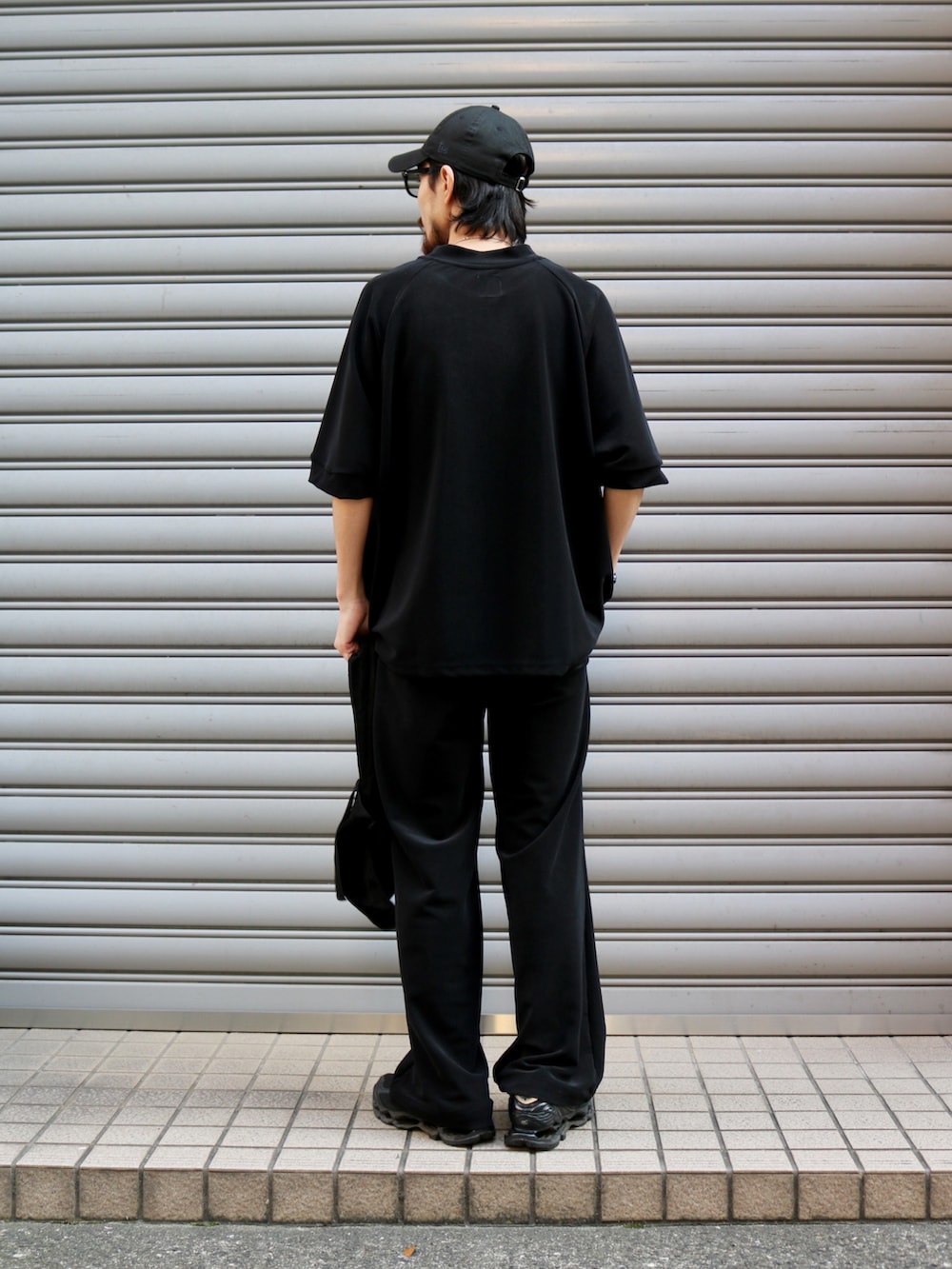 ブラック系のTシャツ/カットソー、ブラック系のトートバッグ、ブラック系のスラックスを着用したメンズの夏コーディネートの3枚目の写真