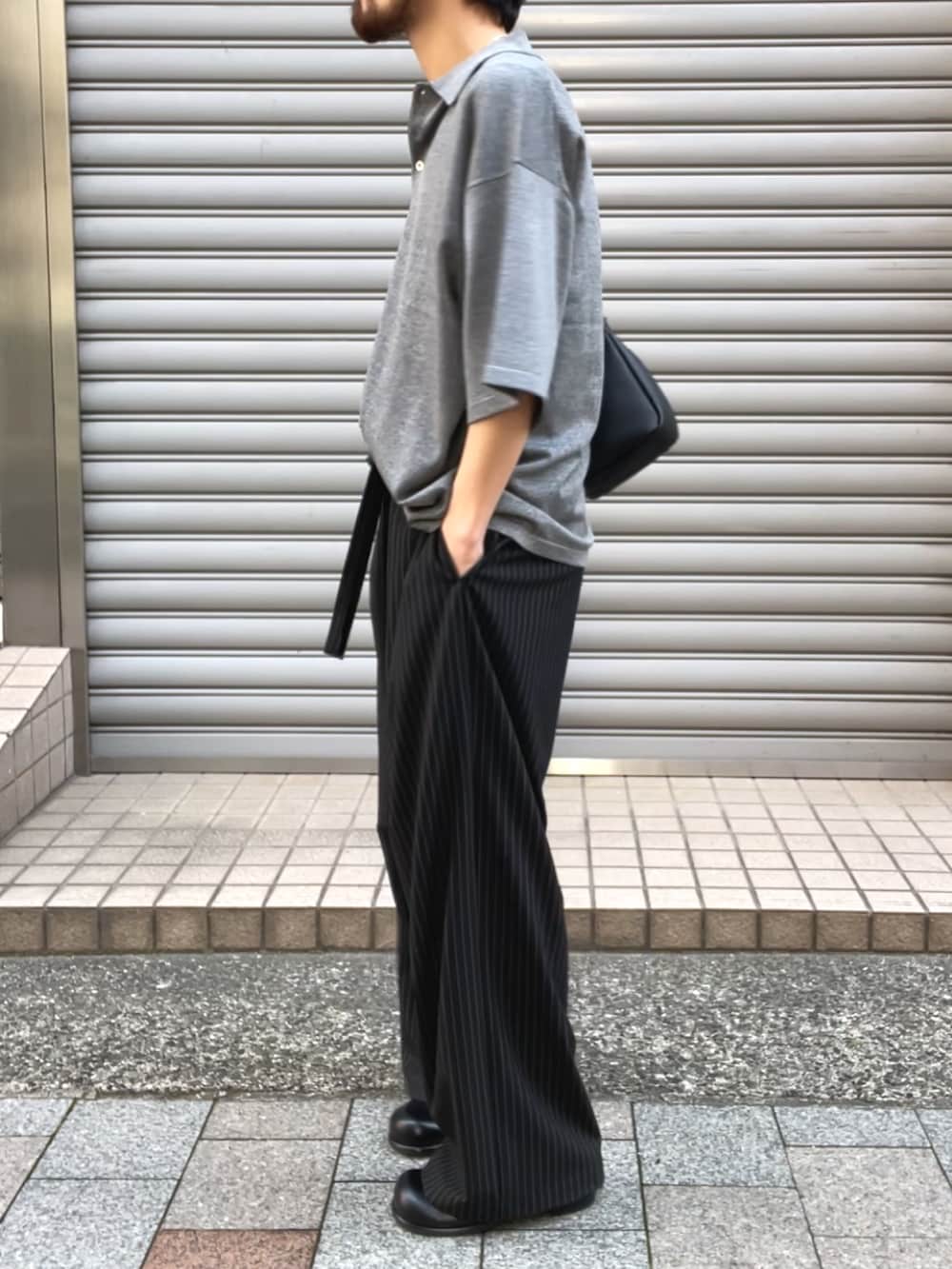 ブラック系のその他シューズ、グレー系のニット/セーター、ブラック系のショルダーバッグを着用したメンズの夏コーディネートの2枚目の写真