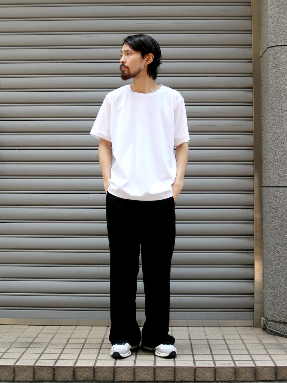 ブラック系のスラックス、ブラック系のトートバッグ、ホワイト系のTシャツ/カットソーを着用したメンズの夏コーディネートの3枚目の写真