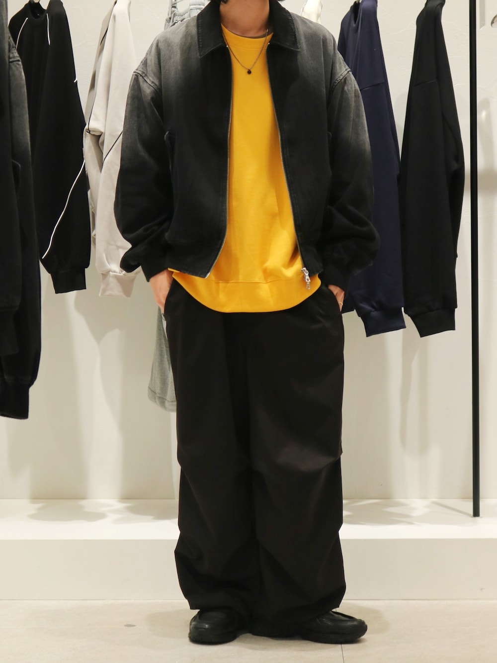 ブラック系のブルゾン、ブラック系のスニーカー、イエロー系のスウェットを着用したメンズの秋コーディネートの2枚目の写真