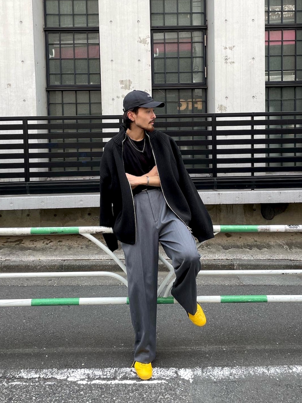 イエロー系のスニーカー、ブラック系のニット/セーター、グレー系のスラックスを着用したメンズの秋コーディネートの3枚目の写真