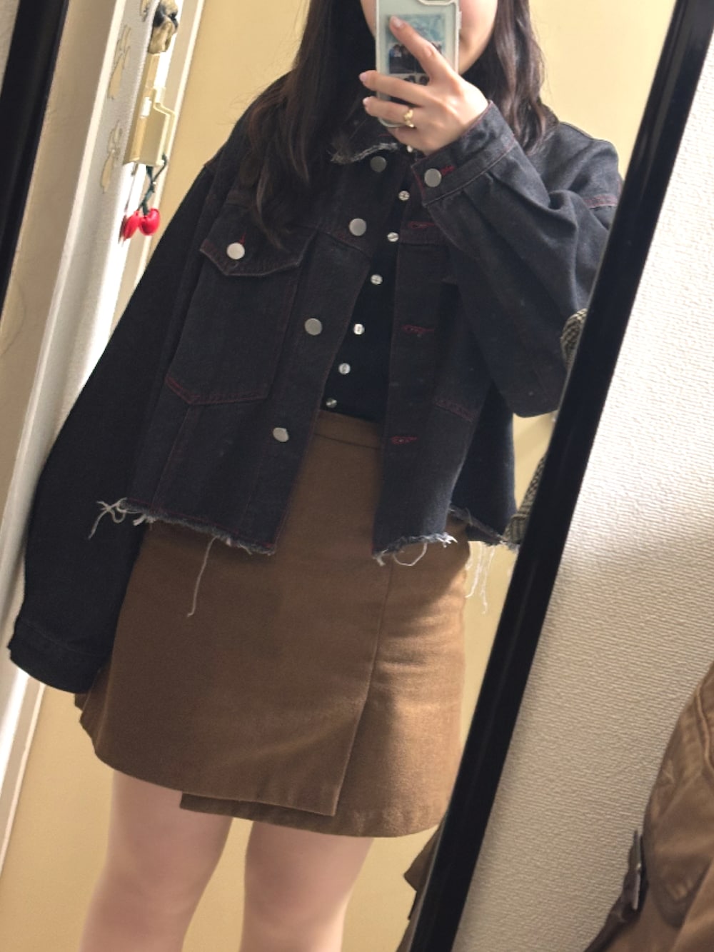 ブラック系のデニムジャケット、ブラック系のニット/セーター、ベージュ系のスカートを着用したレディースの冬コーディネートの2枚目の写真