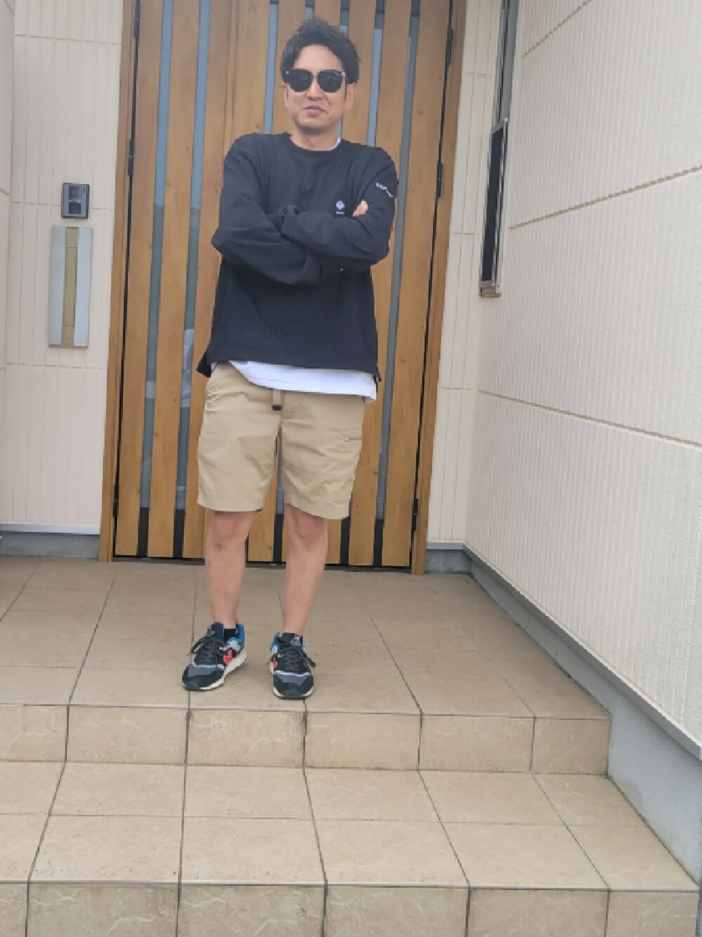 ベージュ系のパンツ、ブラック系のTシャツ/カットソー、ブラック系のスニーカーを着用したメンズの夏コーディネートの2枚目の写真