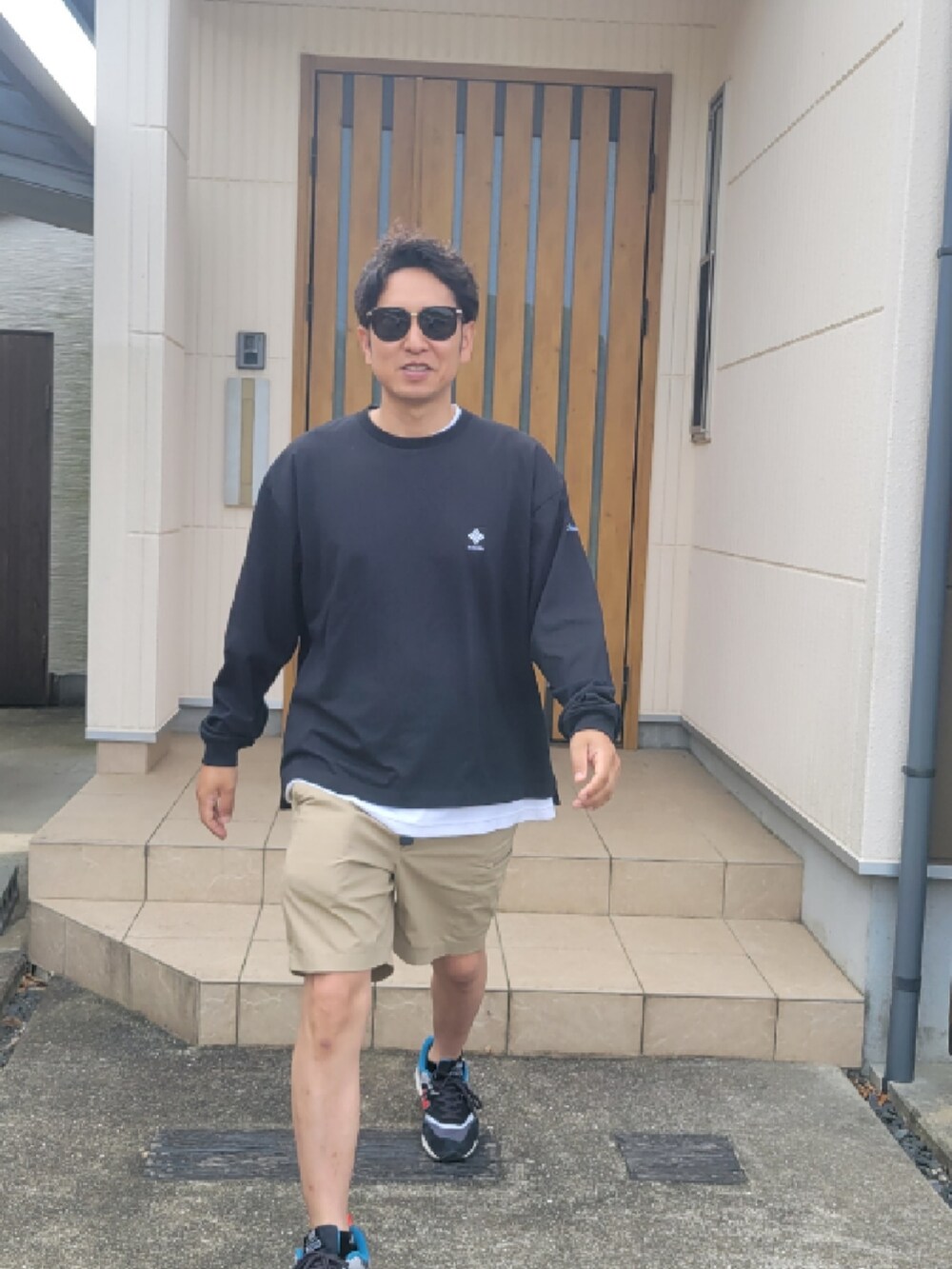 ベージュ系のパンツ、ブラック系のTシャツ/カットソー、ブラック系のスニーカーを着用したメンズの夏コーディネートの3枚目の写真