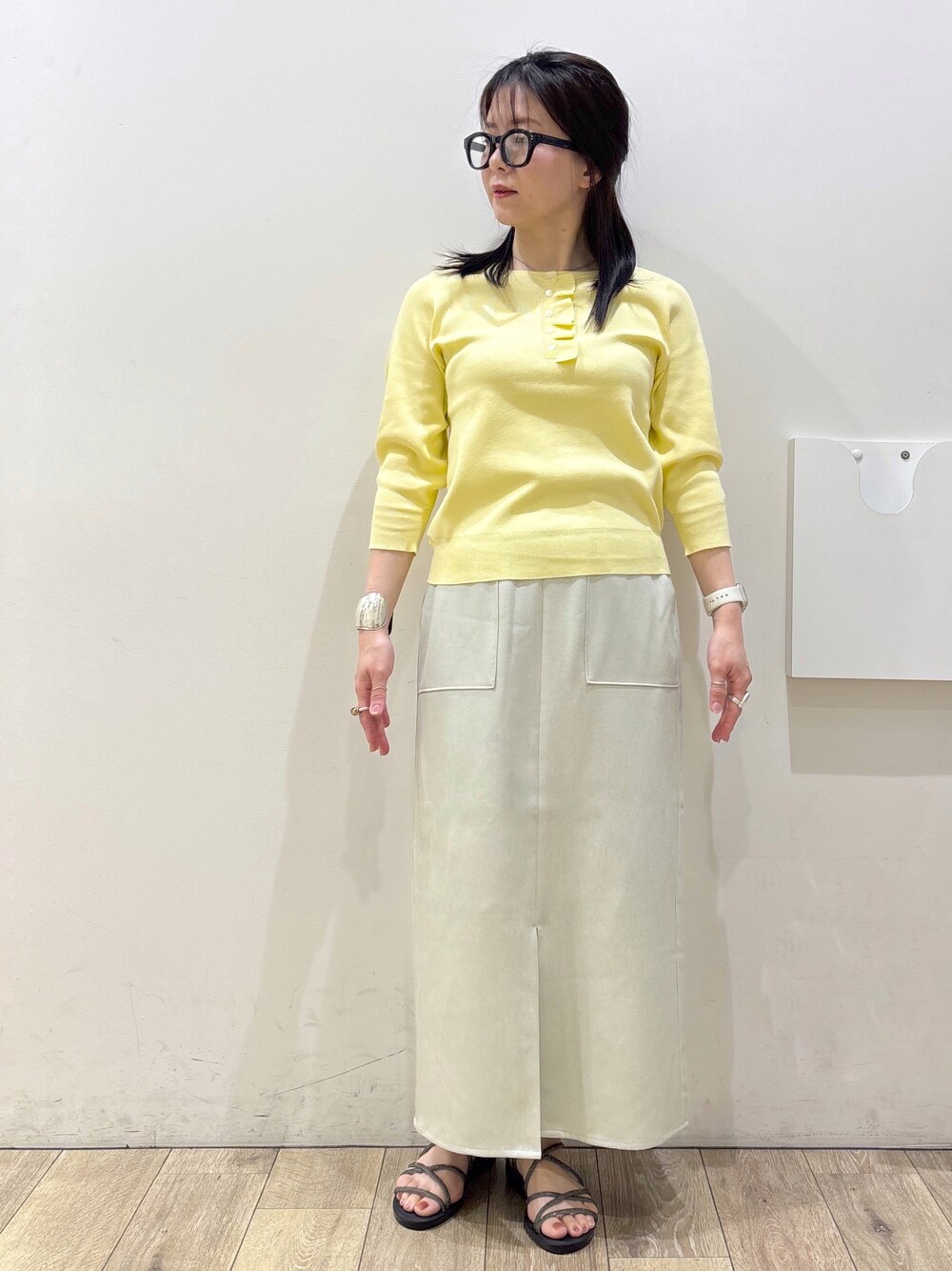 イエロー系のニット/セーター、ベージュ系のスカート、ホワイト系のトートバッグを着用したレディースの春コーディネートの6枚目の写真