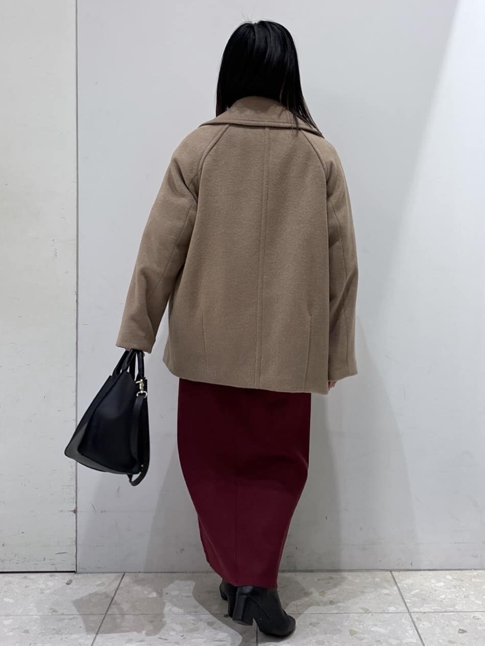 ベージュ系のピーコート、ブルー系のニット/セーター、レッド系のスカートを着用したレディースの冬コーディネートの3枚目の写真