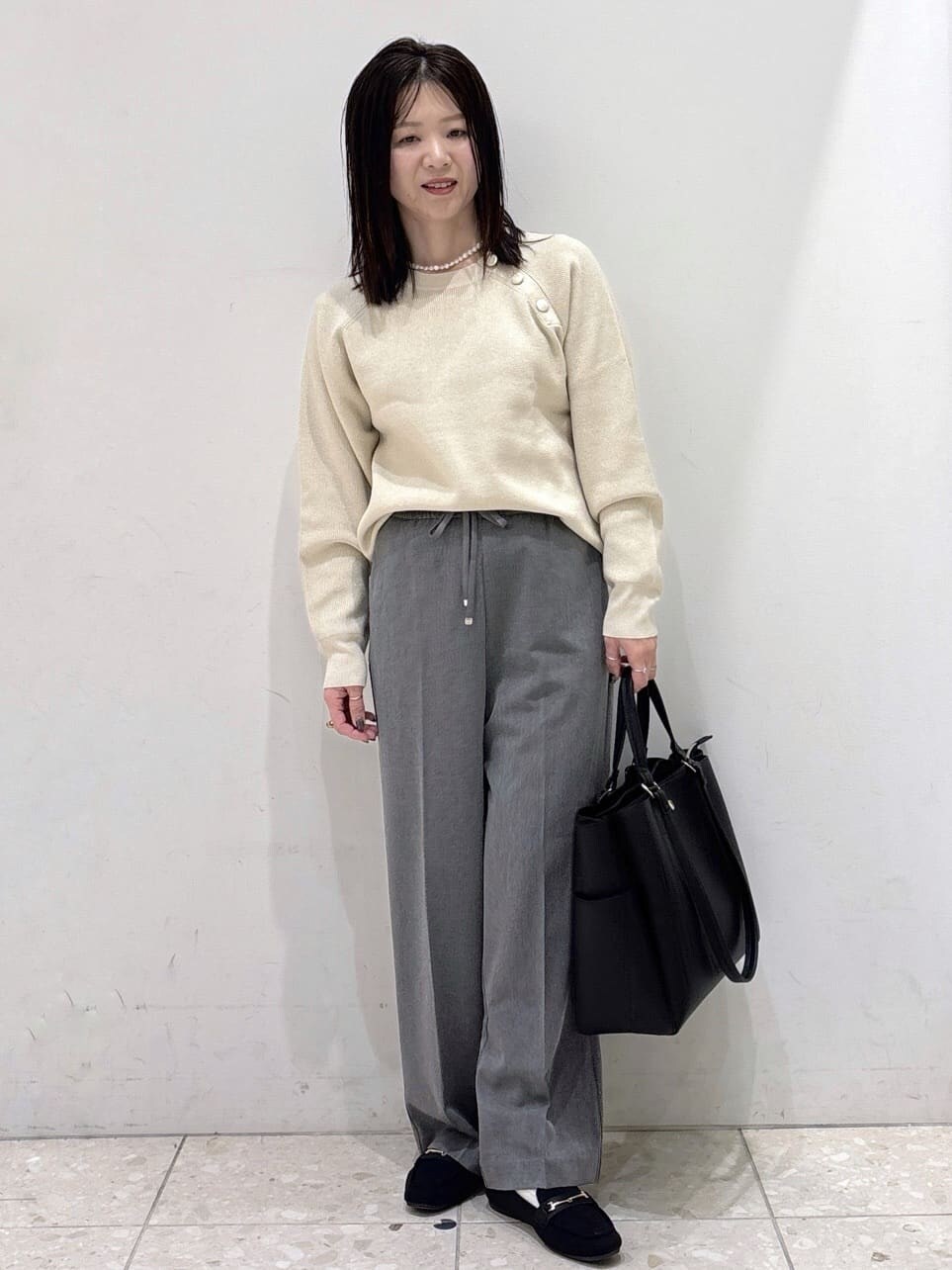 ブラック系のダウンジャケット/コート、ホワイト系のニット/セーター、グレー系のその他パンツを着用したレディースの冬コーディネートの5枚目の写真