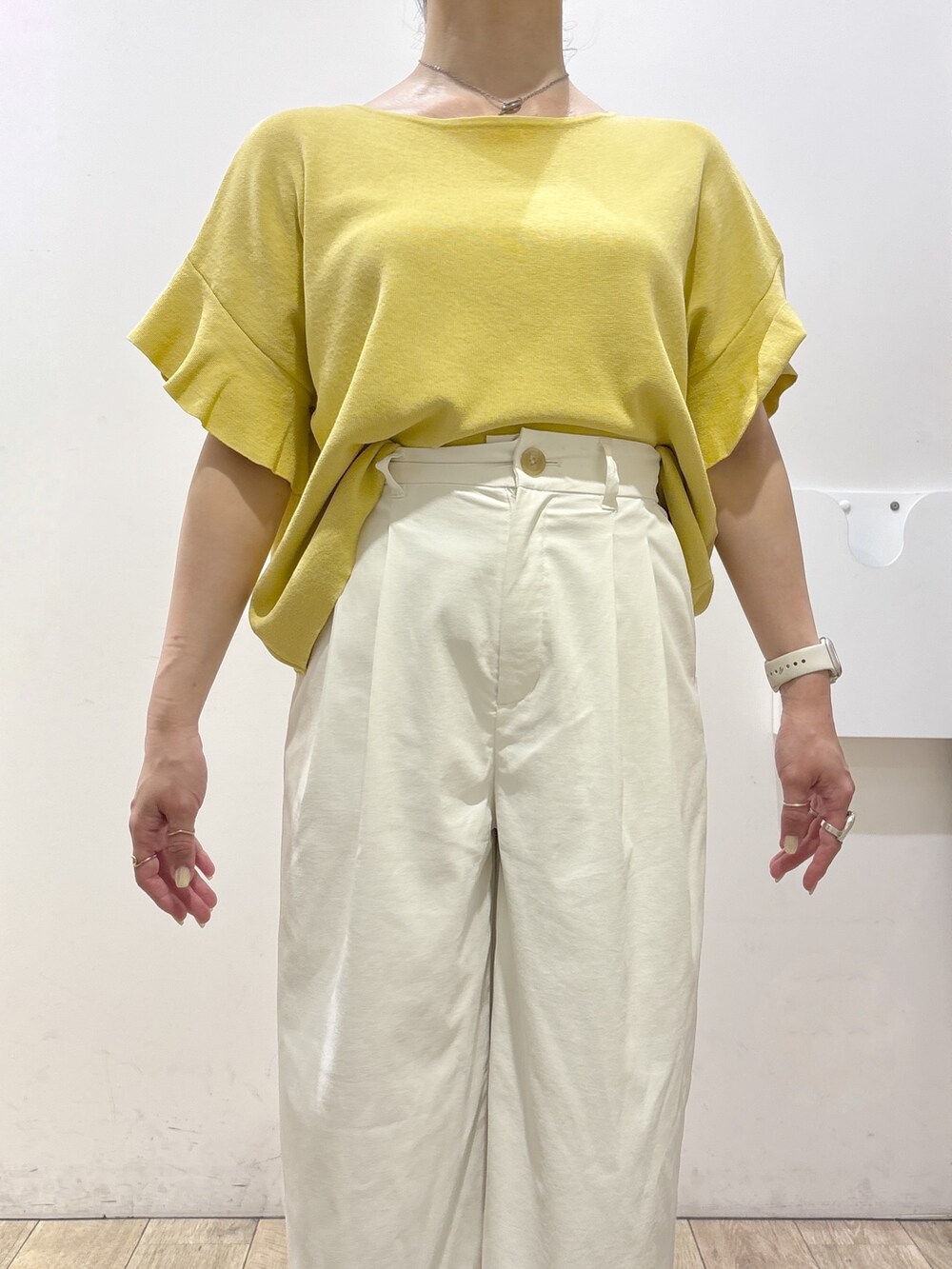イエロー系のニット/セーター、ホワイト系のその他パンツ、ブラウン系のトートバッグを着用したレディースの春コーディネートの6枚目の写真