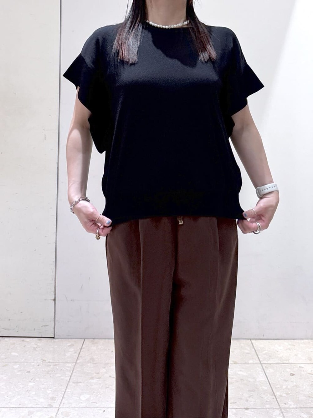ブラック系のニット/セーター、ブラウン系のその他パンツ、ブラック系のトートバッグを着用したレディースの夏コーディネートの7枚目の写真
