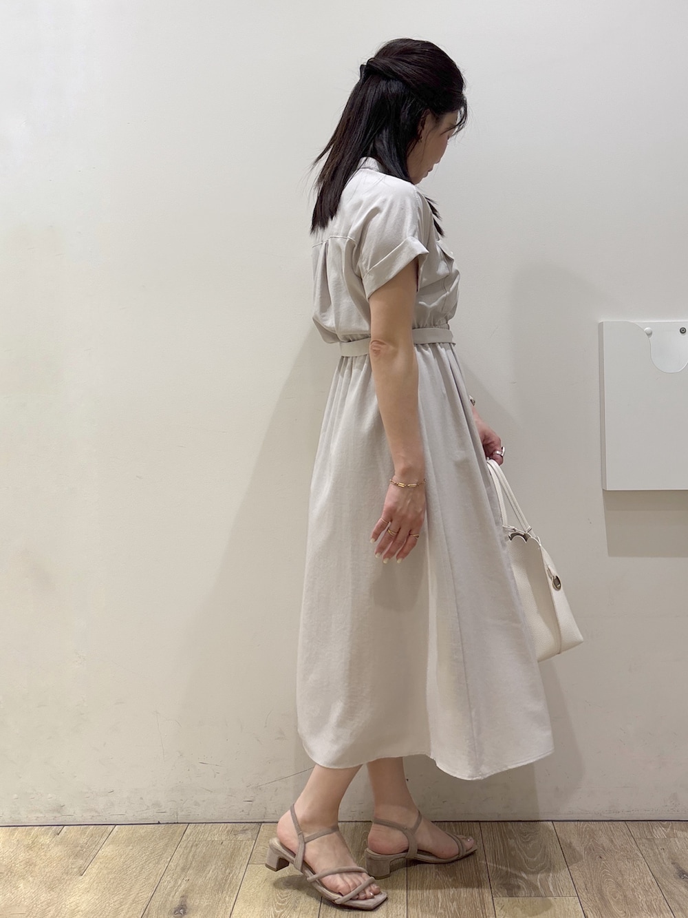 ベージュ系のワンピース、ホワイト系のトートバッグ、ベージュ系のサンダルを着用したレディースの春コーディネートの2枚目の写真