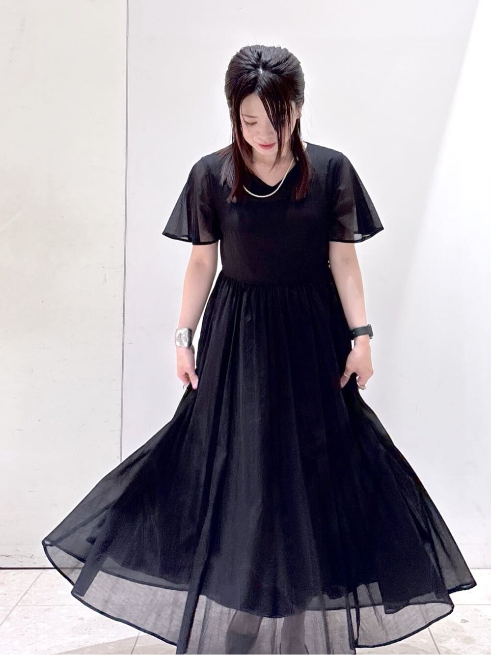 ブラック系のワンピース、ブラック系のトートバッグ、ブラック系のパンプスを着用したレディースの夏コーディネートの8枚目の写真