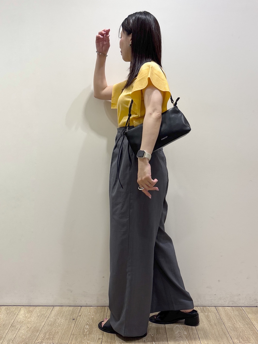 イエロー系のニット/セーター、グレー系のその他パンツ、ブラック系のショルダーバッグを着用したレディースの夏コーディネートの4枚目の写真
