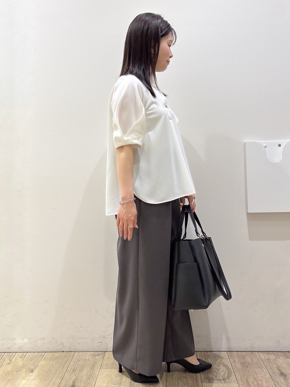 ブラック系のトートバッグ、ブラック系のパンプス、ホワイト系のシャツ/ブラウスを着用したレディースの春コーディネートの2枚目の写真