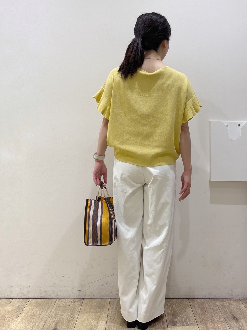イエロー系のニット/セーター、ホワイト系のその他パンツ、ブラウン系のトートバッグを着用したレディースの春コーディネートの3枚目の写真