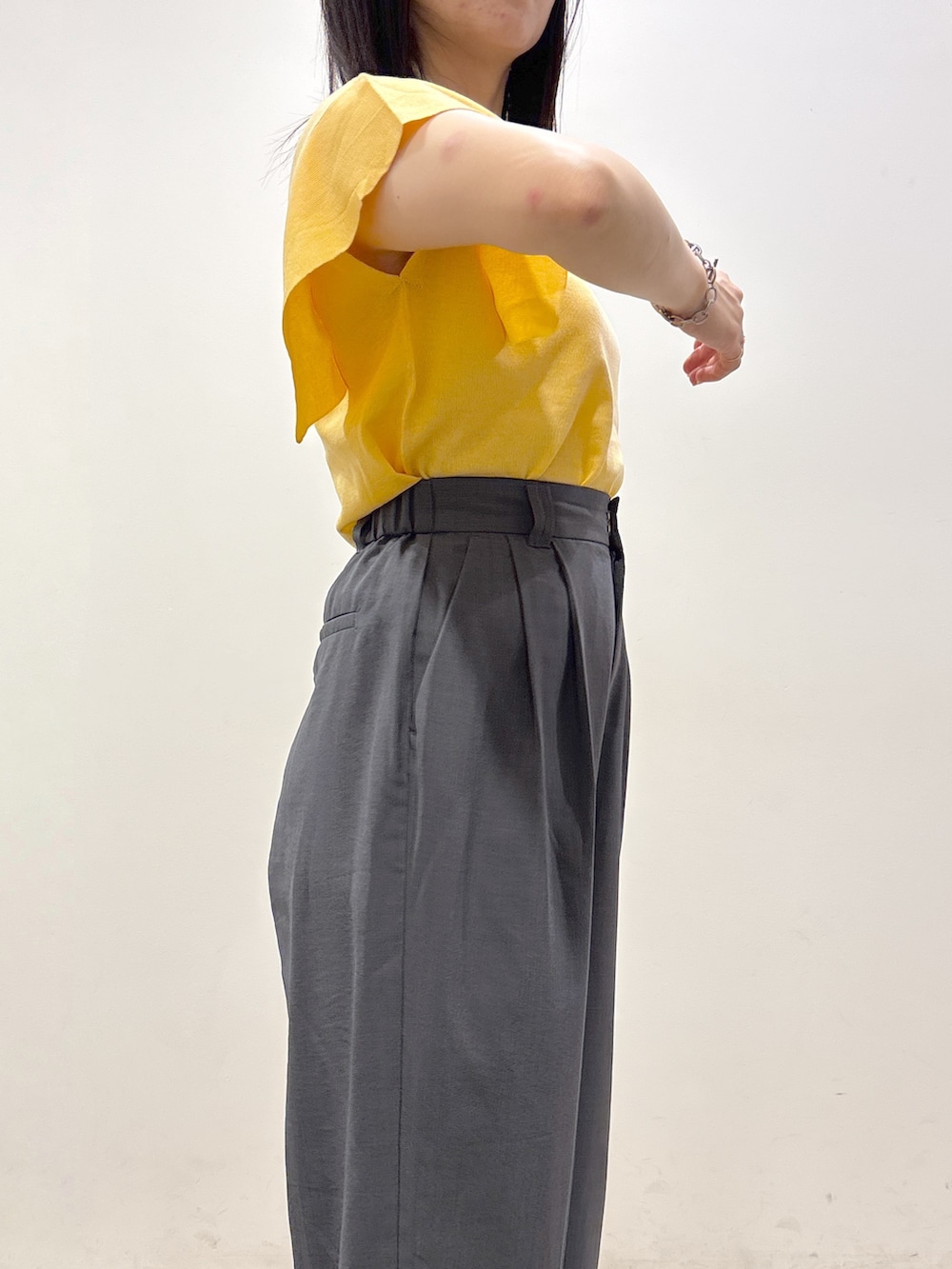 イエロー系のニット/セーター、グレー系のその他パンツ、ブラック系のショルダーバッグを着用したレディースの夏コーディネートの8枚目の写真