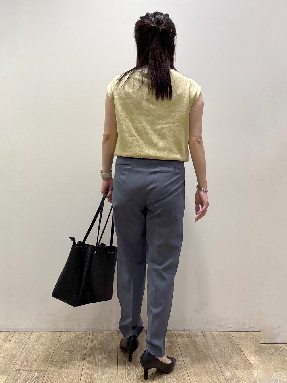 イエロー系のニット/セーター、グレー系のその他パンツ、ブラック系のトートバッグを着用したレディースの夏コーディネートの4枚目の写真