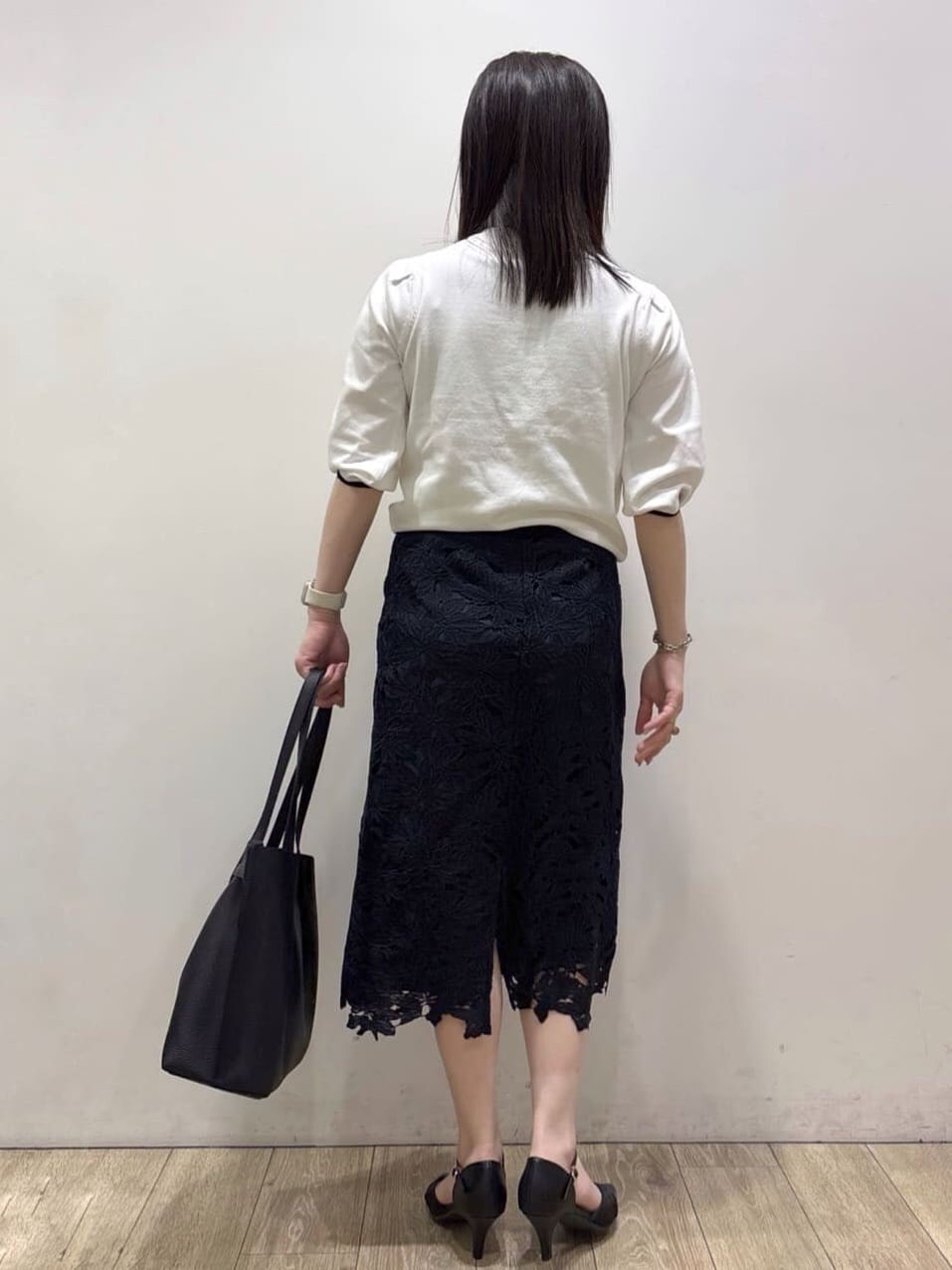 ブルー系のスカート、ブラック系のパンプス、ブラック系のトートバッグを着用したレディースの春コーディネートの6枚目の写真