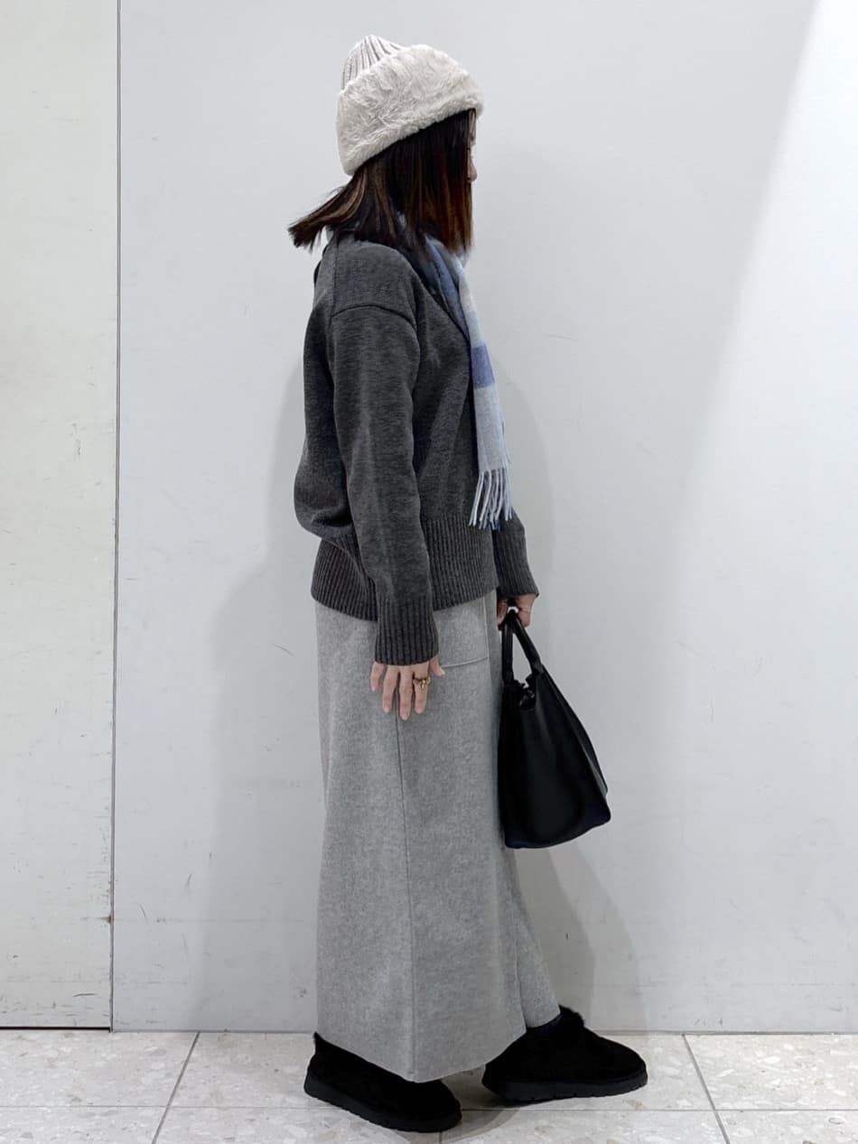 グレー系のニット/セーター、グレー系のスカート、ブラック系のショルダーバッグを着用したレディースの冬コーディネートの2枚目の写真