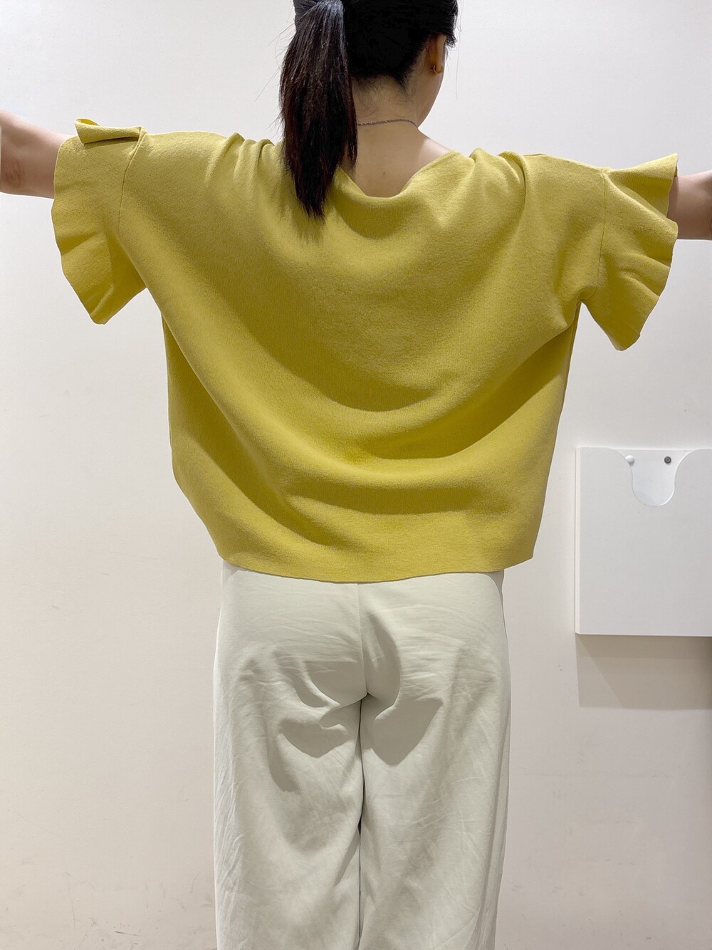 イエロー系のニット/セーター、ホワイト系のその他パンツ、ブラウン系のトートバッグを着用したレディースの春コーディネートの8枚目の写真