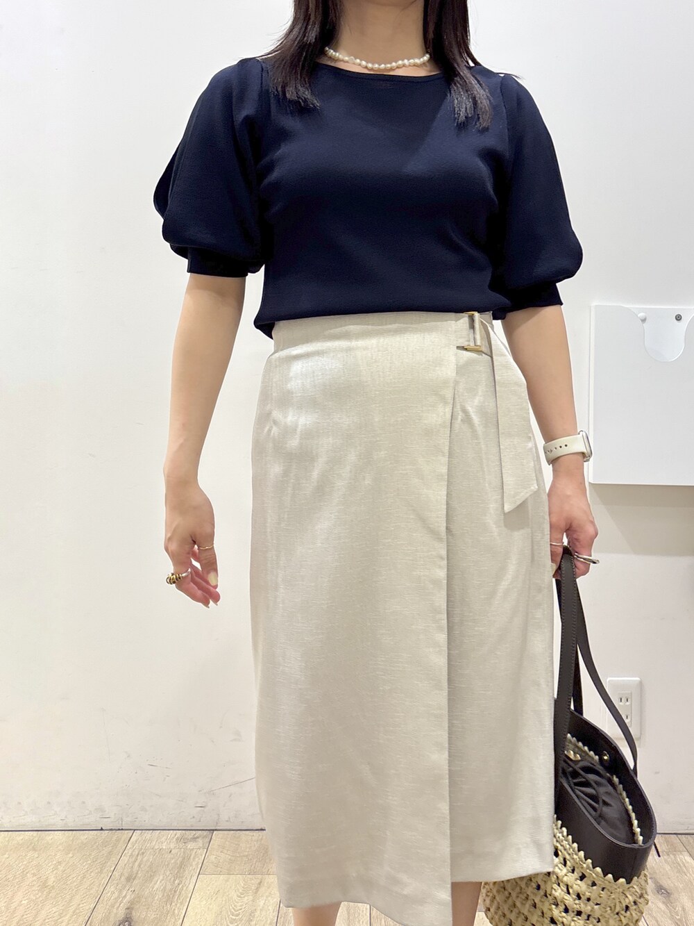 ブルー系のニット/セーター、ベージュ系のスカート、ブラウン系のトートバッグを着用したレディースの夏コーディネートの8枚目の写真
