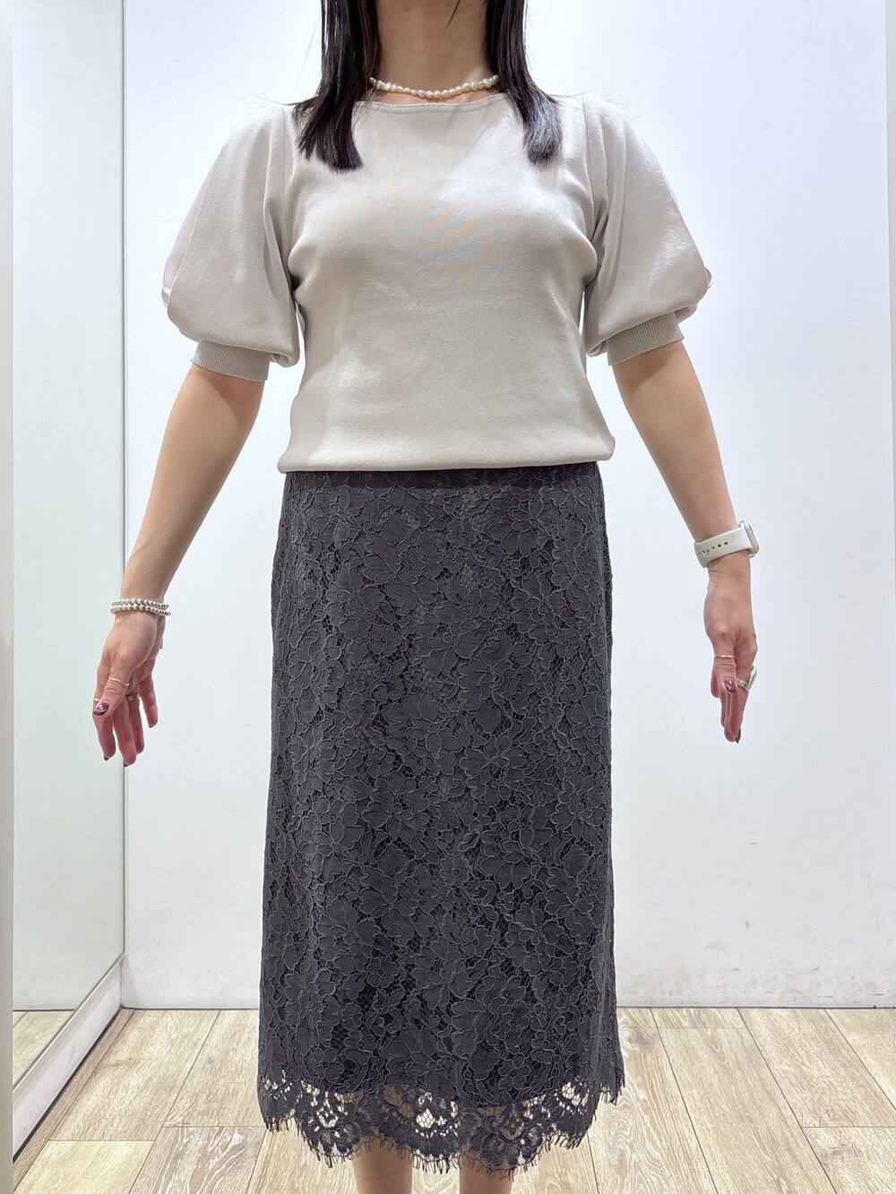 ベージュ系のニット/セーター、グレー系のスカート、ブラック系のトートバッグを着用したレディースの夏コーディネートの6枚目の写真