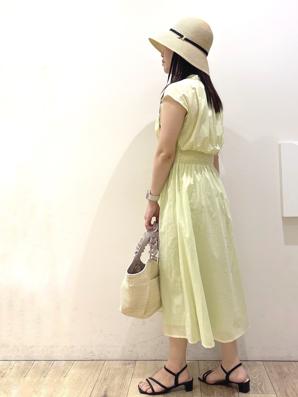 イエロー系のワンピース、ベージュ系のトートバッグ、ブラック系のサンダルを着用したレディースの夏コーディネートの4枚目の写真