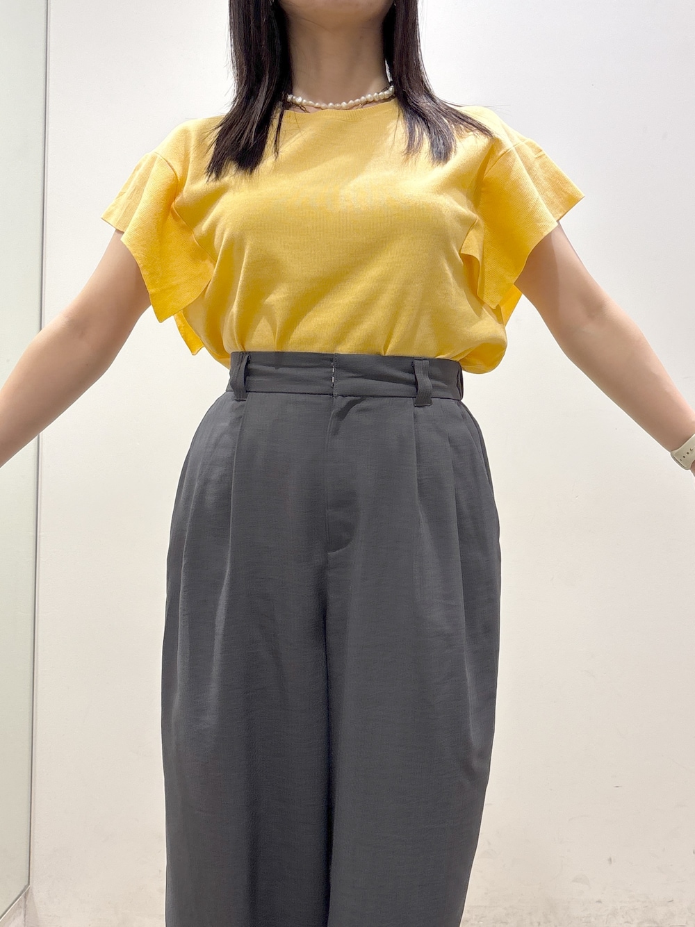 イエロー系のニット/セーター、グレー系のその他パンツ、ブラック系のショルダーバッグを着用したレディースの夏コーディネートの7枚目の写真