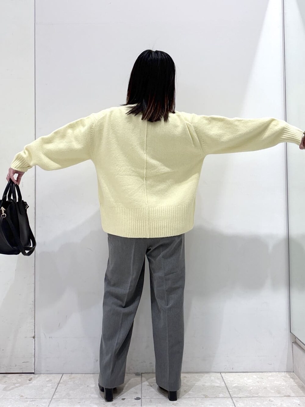 イエロー系のニット/セーター、グレー系のその他パンツ、ブラック系のショルダーバッグを着用したレディースの冬コーディネートの4枚目の写真