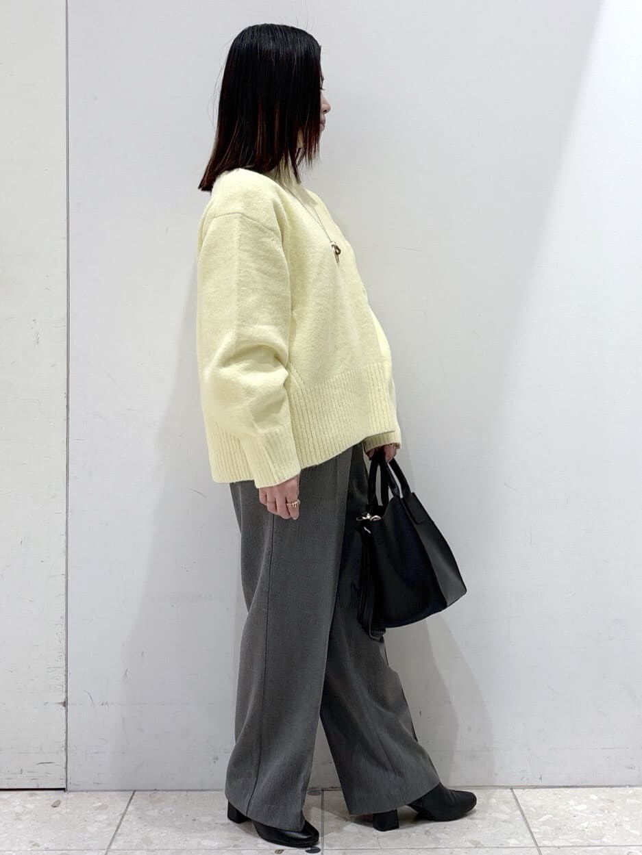 イエロー系のニット/セーター、グレー系のその他パンツ、ブラック系のショルダーバッグを着用したレディースの冬コーディネートの2枚目の写真