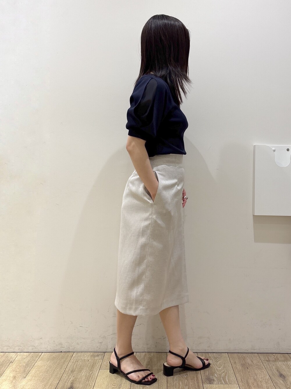 ブルー系のニット/セーター、ベージュ系のスカート、ブラウン系のトートバッグを着用したレディースの夏コーディネートの6枚目の写真