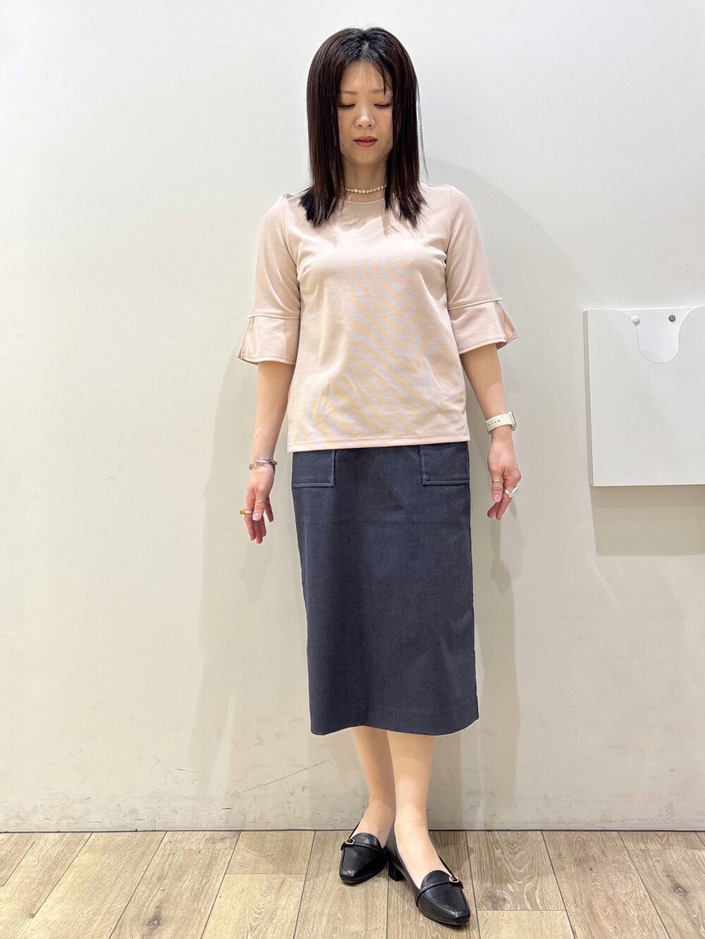 ブラック系のパンプス、ブラック系のトートバッグ、ブルー系のスカートを着用したレディースの春コーディネートの8枚目の写真