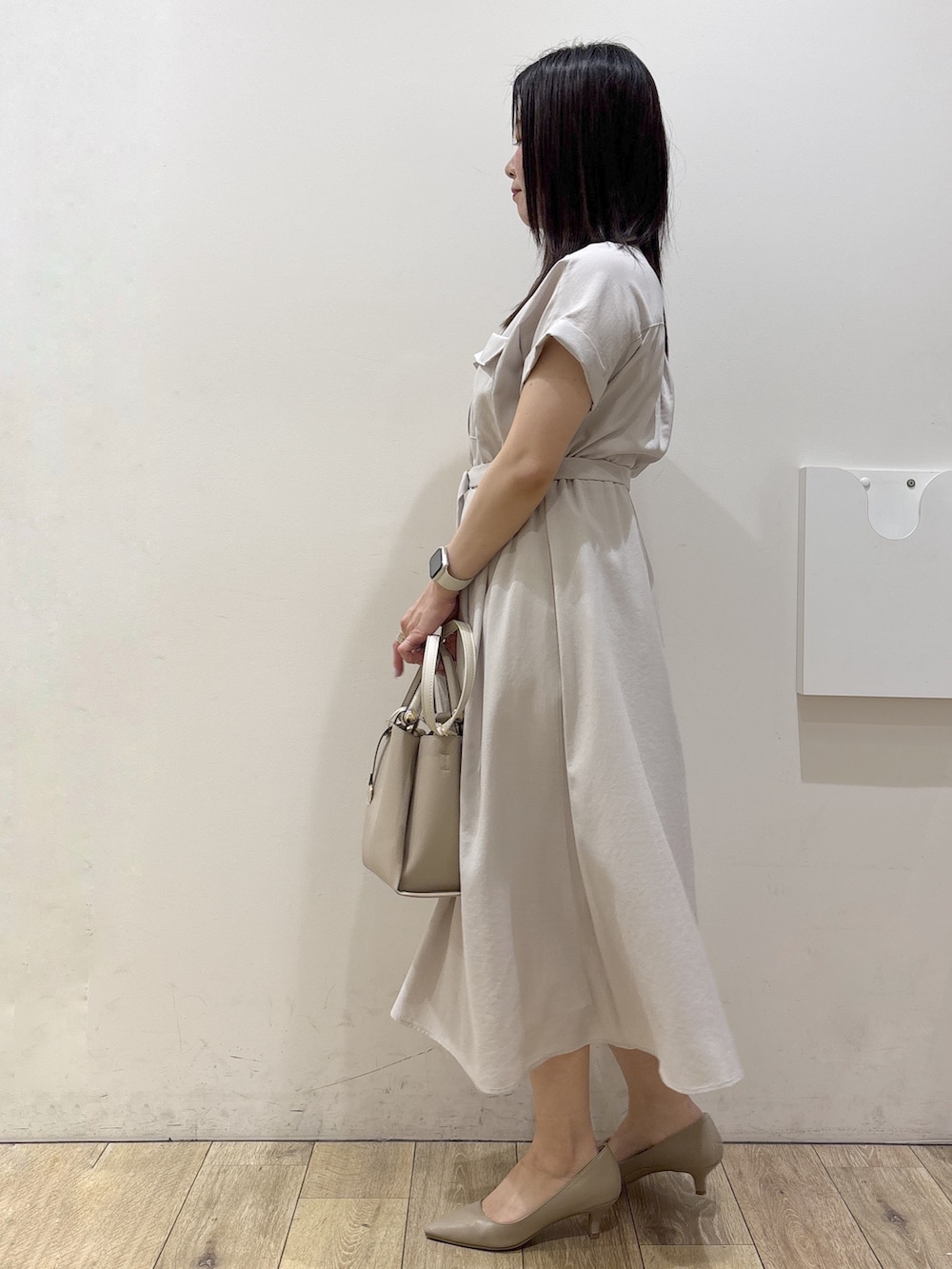 ベージュ系のワンピース、ベージュ系のトートバッグ、ベージュ系のパンプスを着用したレディースの夏コーディネートの5枚目の写真