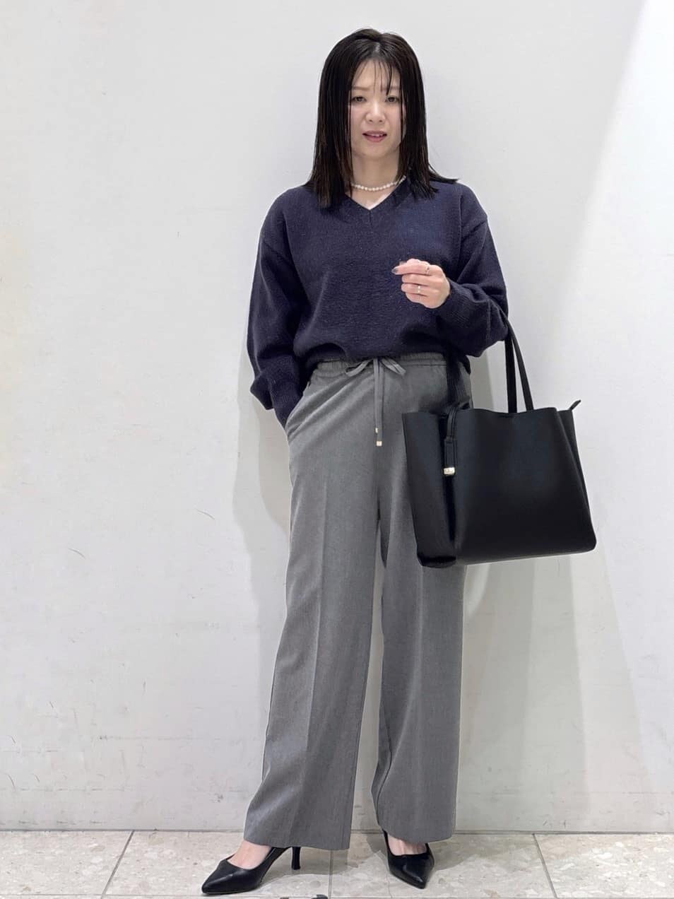 ブルー系のニット/セーター、グレー系のその他パンツ、ブラック系のトートバッグを着用したレディースの冬コーディネートの7枚目の写真